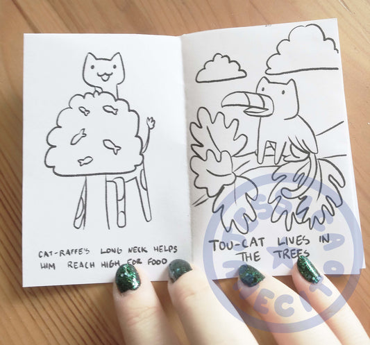 a mini zine is opened to show a picture on the left of the cat-raffe eating from a tree with small fish on the branches. The right page is a picture of a cat with wings and a beak sitting in a tree
